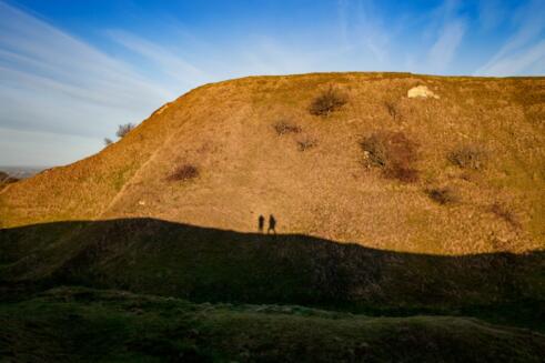 Two figures silhouetted against Cley Hill, Wiltshire, Uk